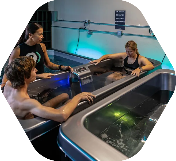 Clients in the cold plunge with a coach alongside