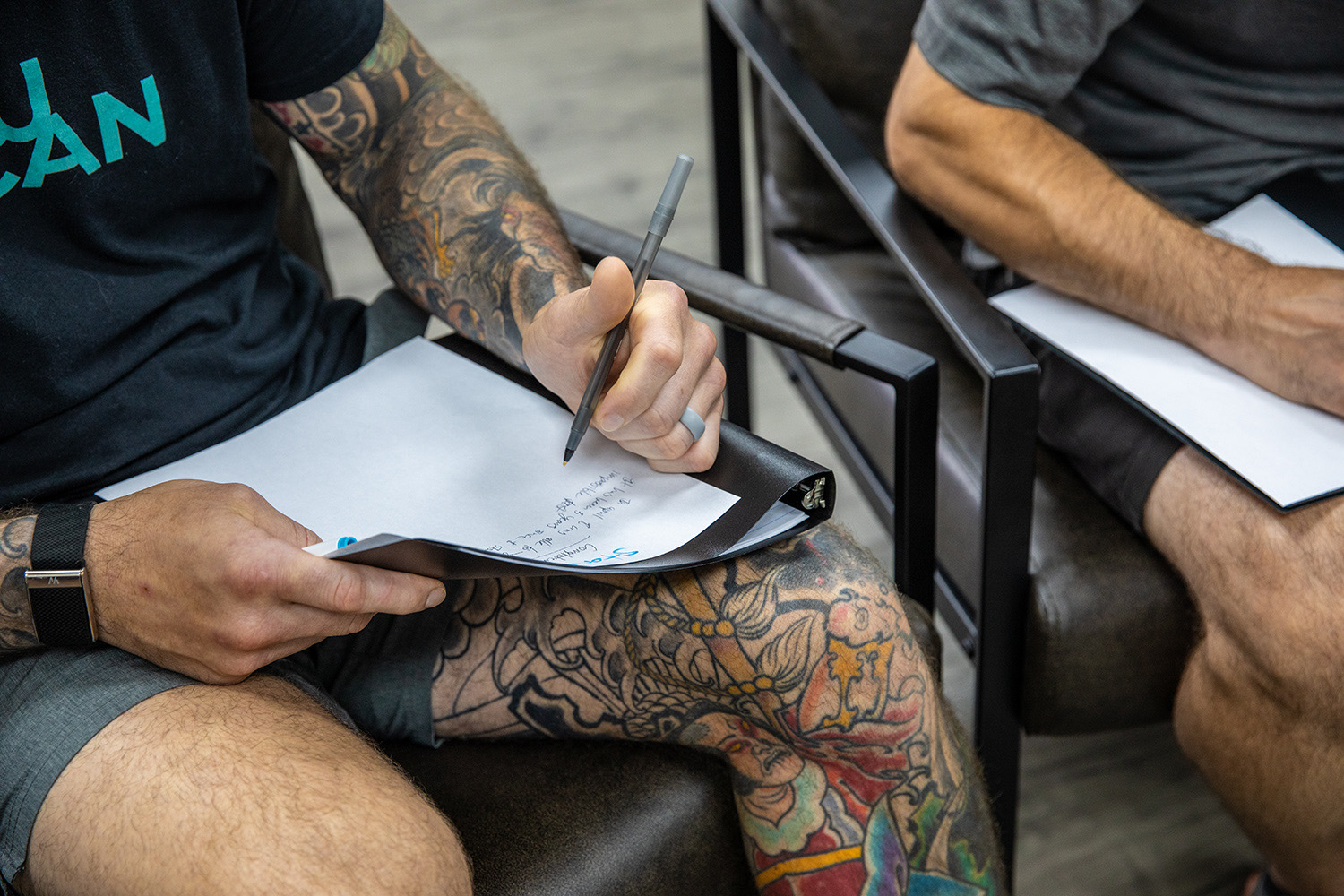 A client writing in a workbook during a group session at e-motion wellness®